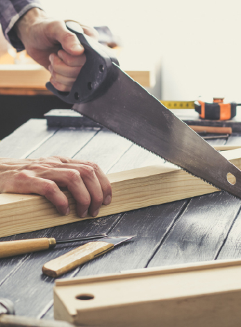 Un homme scie une planche de bois