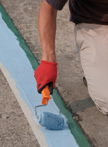 un homme peint sur le sol la signalétique du parking
