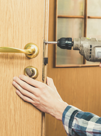 un homme utilise une perceuse sur une porte
