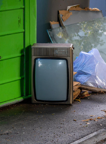 une vieille télé et des gros déchets à coté d'une poubelle