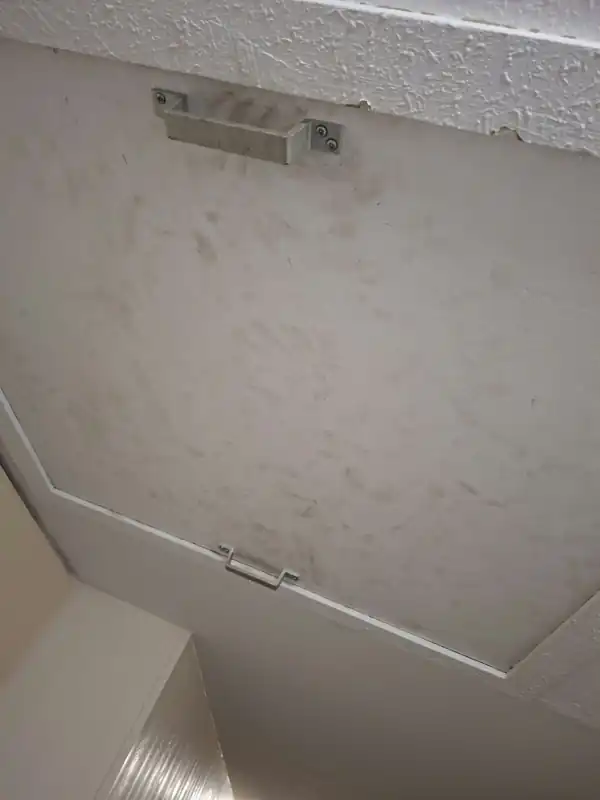 Trappe de visite encrassée au plafond d’un couloir, avant intervention